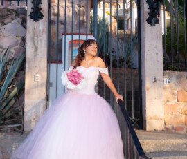 Quinceañera con vestido claro frente a una reja