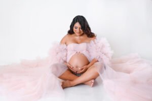 Retrato de maternidad con vestido rosa en estudio