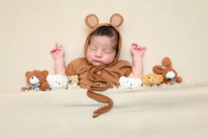 Bebé recién nacido con gorro de oso y pequeños peluches