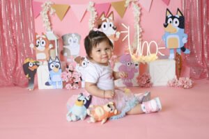 Bebé con pastel en un escenario rosa de cumpleaños