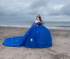 Quinceañera con vestido azul junto al mar