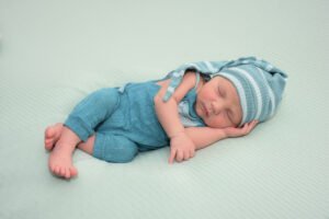 Bebé recién nacido dormido con gorro y ropa azul