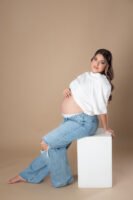 Retrato de maternidad con pantalones de mezclilla en estudio