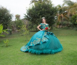 Quinceañera con vestido turquesa en un jardín