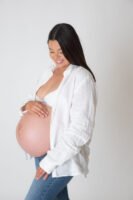 Retrato de maternidad con pantalones de mezclilla en estudio