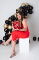 Retrato de cumpleaños con vestido rojo, ramo y globos negros