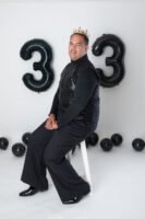 Retrato de cumpleaños junto a globos negros con el número 33