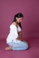 Retrato de maternidad con pantalones de mezclilla en estudio
