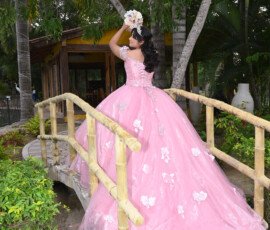Quinceañera con vestido rosa junto a una barandilla