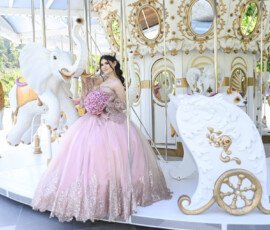 Quinceañera con vestido lila junto a un carrusel