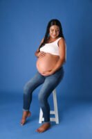 Retrato de maternidad con pantalones de mezclilla en estudio