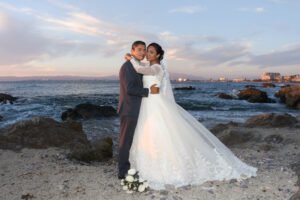 Retrato de novios junto al mar con el velo extendido