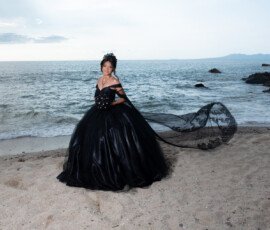 Quinceañera con vestido negro frente al mar