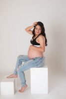 Retrato de maternidad con pantalones de mezclilla en estudio