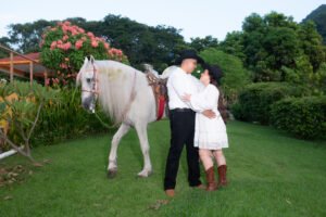 Pareja junto a un caballo blanco en un jardín