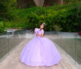 Quinceañera con vestido lila en un sendero