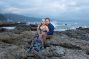 Pareja sentada sobre rocas junto al mar