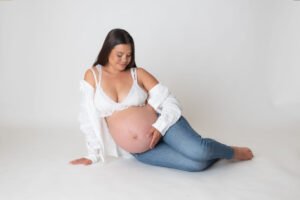 Retrato de maternidad con pantalones de mezclilla en estudio