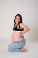 Retrato de maternidad con pantalones de mezclilla en estudio