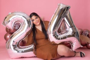 Retrato de cumpleaños con globos plateados sobre fondo rosa