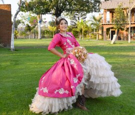 Quinceañera con vestido rosa junto a una fuente
