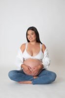 Retrato de maternidad sentada con las manos sobre el vientre