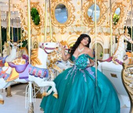 Quinceañera con vestido turquesa junto a un carrusel