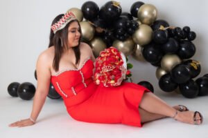 Retrato de cumpleaños con vestido rojo, ramo y globos negros