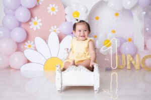 Bebé sentado en un sillón con flores y globos