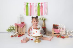 Bebé en una sesión de cumpleaños con pastel y flores