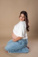 Retrato de maternidad con pantalones de mezclilla en estudio