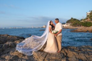 Retrato de novios junto al mar con el velo extendido