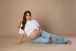 Retrato de maternidad con pantalones de mezclilla en estudio