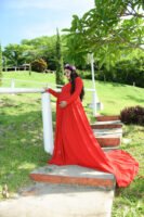 Retrato de maternidad con vestido rojo en un jardín