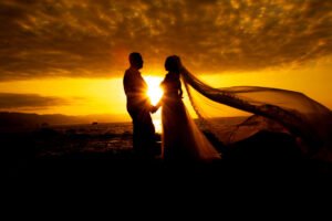 Silueta de novios con el velo al atardecer
