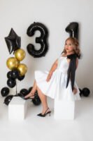 Retrato de cumpleaños con vestido blanco y globos negros y dorados