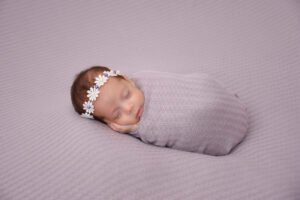 Bebé recién nacido dormido envuelto en una manta lila