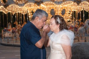 Pareja besándose junto a un carrusel iluminado