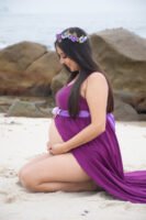 Retrato de maternidad con vestido morado junto al mar