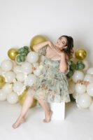 Retrato de cumpleaños con vestido floral y globos claros