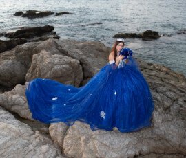 Quinceañera con vestido azul junto al mar