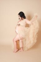 Retrato de maternidad con vestido de tul sobre fondo beige