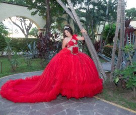 Quinceañera con vestido rojo en un jardín