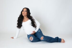 Retrato de maternidad sentada en estudio con camisa blanca
