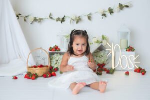 Bebé en una sesión de cumpleaños con pastel y flores