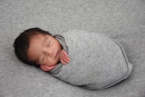 Bebé recién nacido dormido envuelto en una manta gris