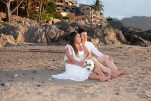 Pareja sentada en la arena frente al mar