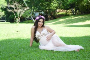 Retrato de maternidad sentada en un jardín