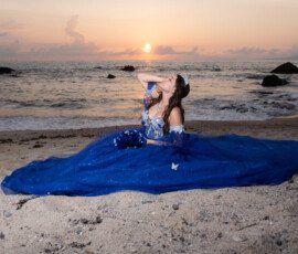 Quinceañera con vestido azul junto al mar