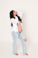 Retrato de maternidad con pantalones de mezclilla en estudio